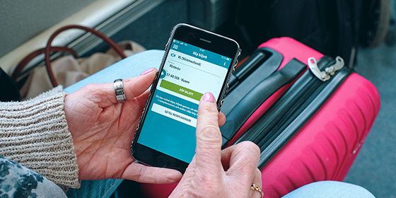 en kvinna som h&aring;ller i en mobilen d&auml;r VL-appen &auml;r &ouml;ppen och hon ska k&ouml;pa en biljett.